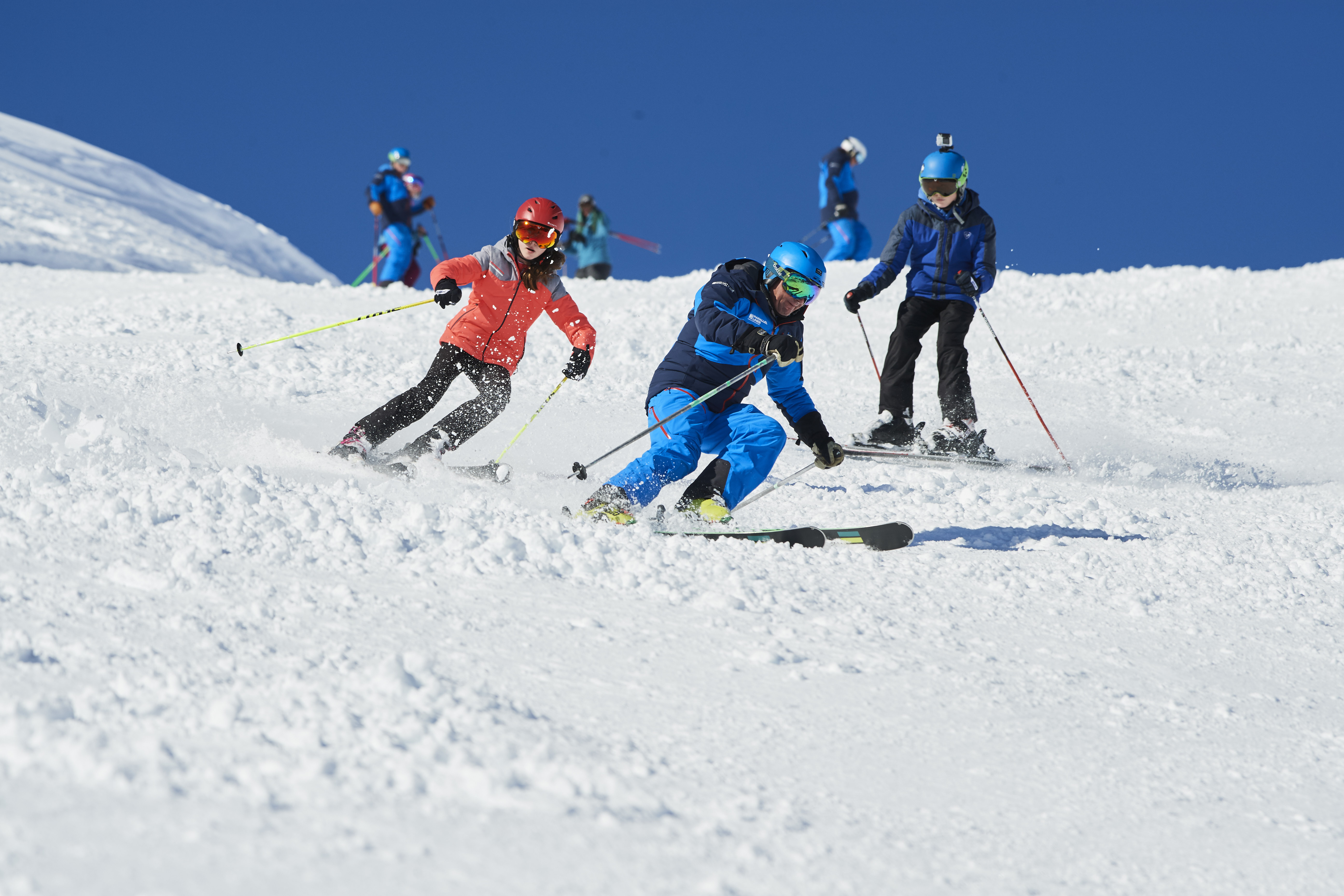 Older children on the ski slopes with instructor.